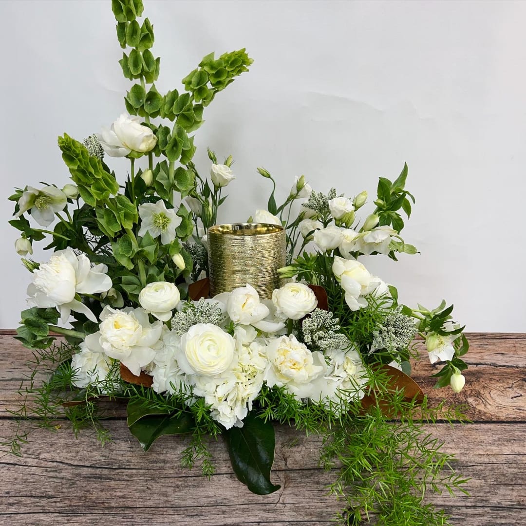 White floral arrangement with a gold candle holder in the center