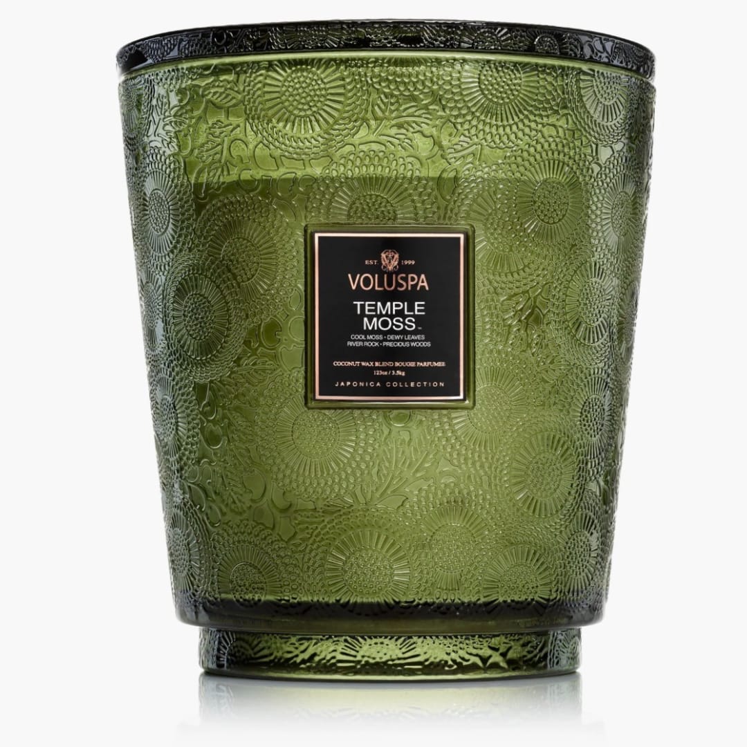 Green patterned glass candle jar with a black label