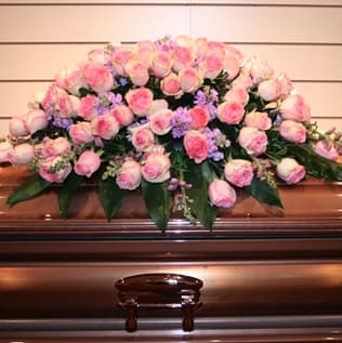 Pink rose casket spray with purple filler flowers