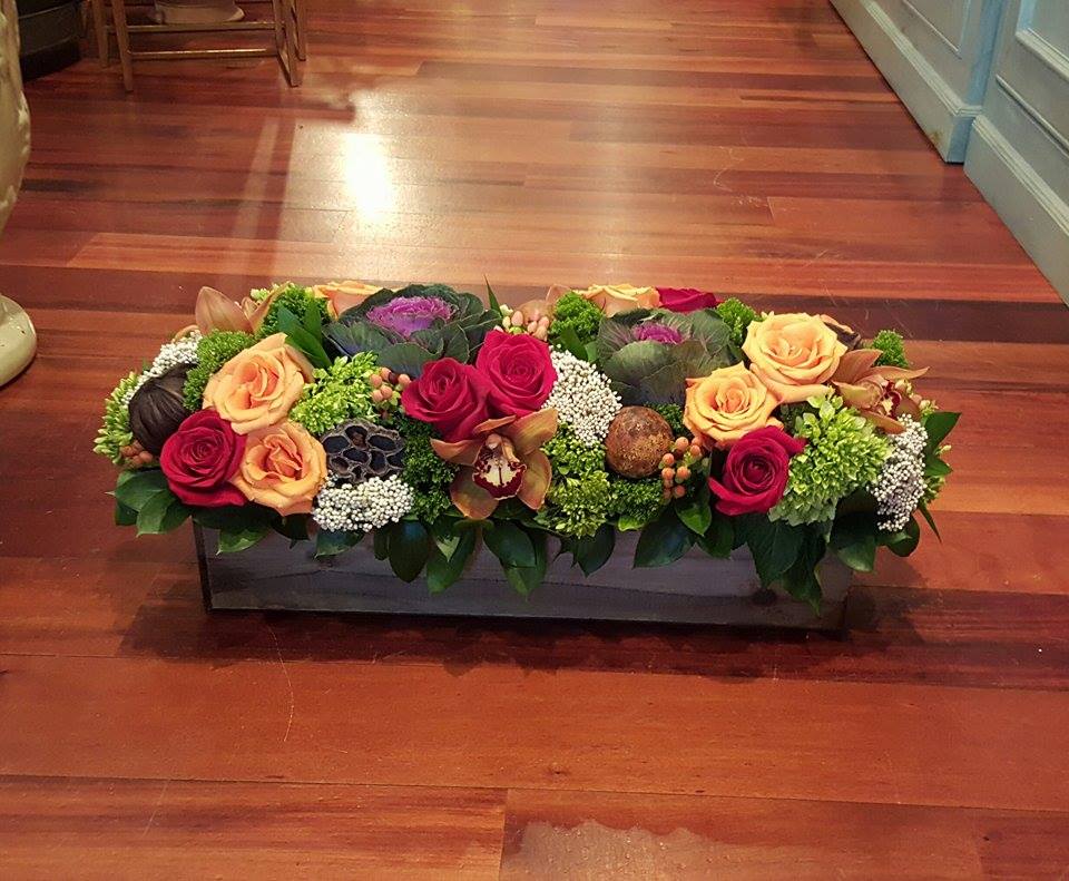 Pilgrim Special - This long and low arrangement is great for the glamourous Thanksgiving table. It is sure to make an impact with orange and red roses, green hydrangea, kale, berries, orchids, pods, and green trick.  It is one of our favorites! 