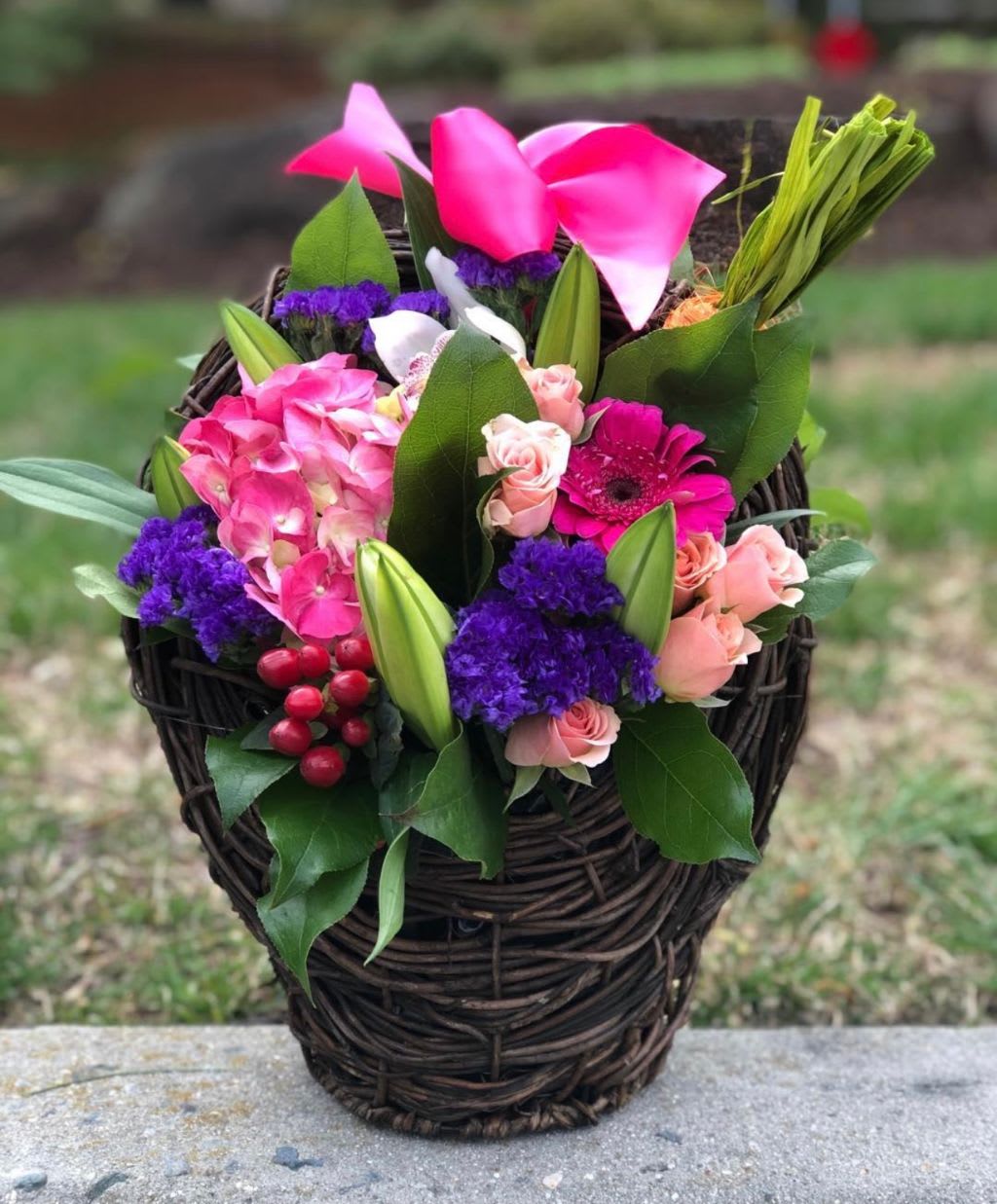 Pink and purple floral basket arrangement with roses and calla lilies