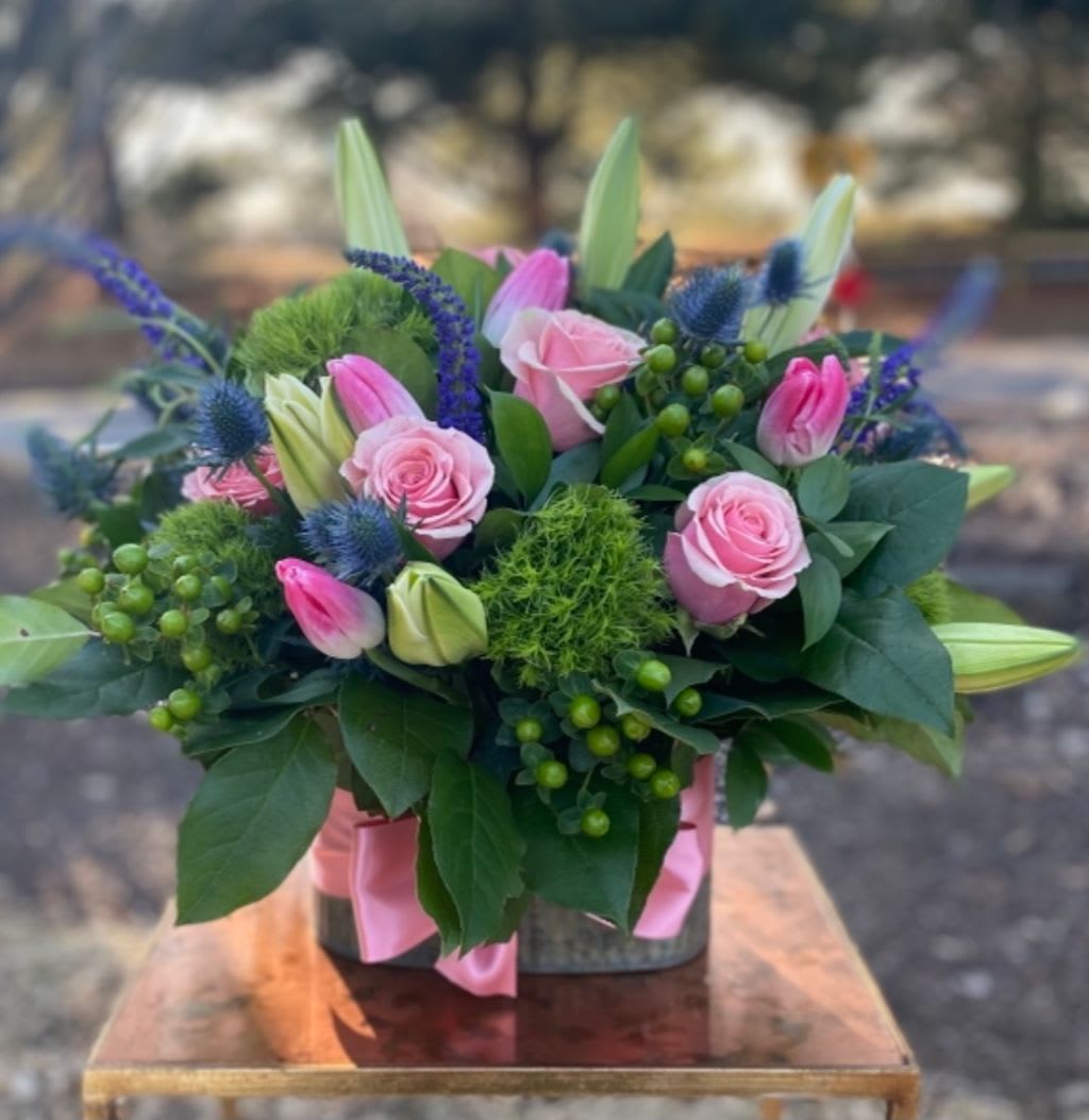 Pink roses and tulips in a low vase arrangement with blue accents