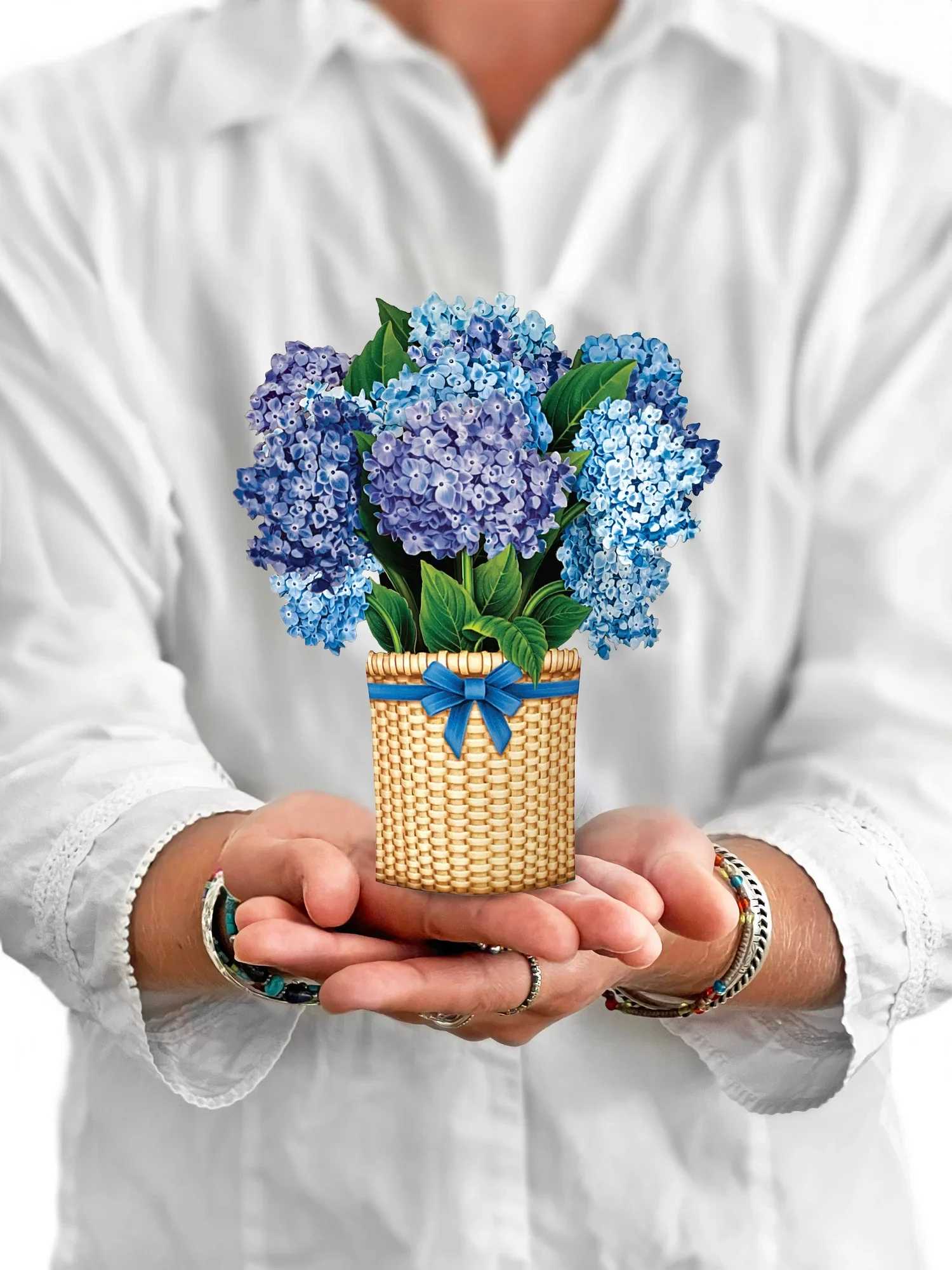 Blue and purple hydrangeas in a woven basket with a ribbon