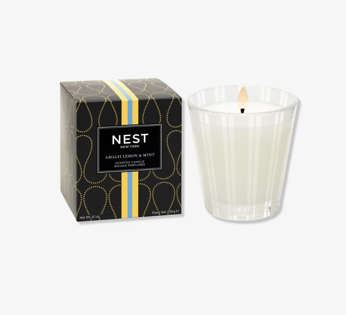 Boxed scented candle beside a lit glass candle