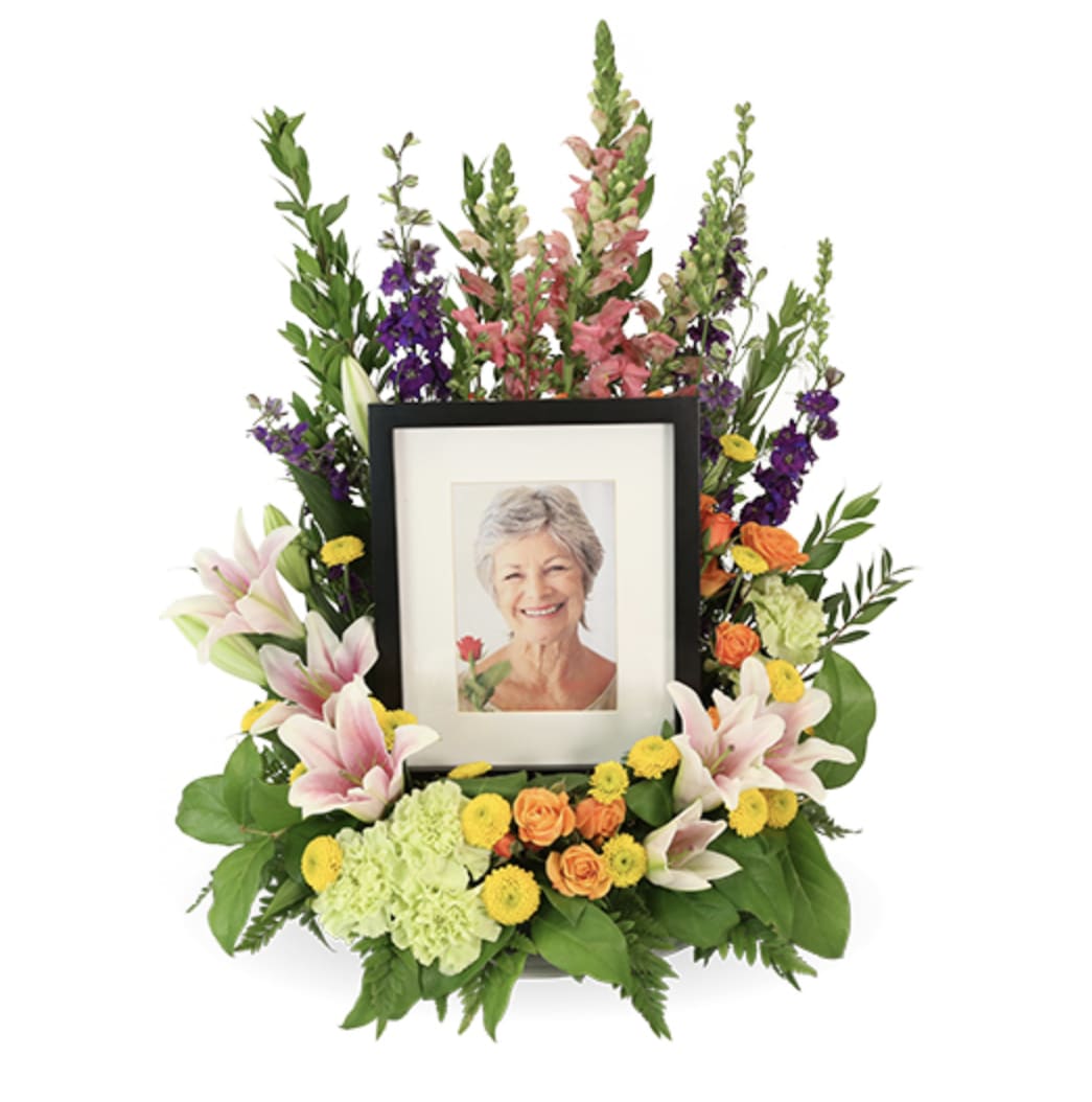 Framed photo surrounded by a colorful floral tribute arrangement