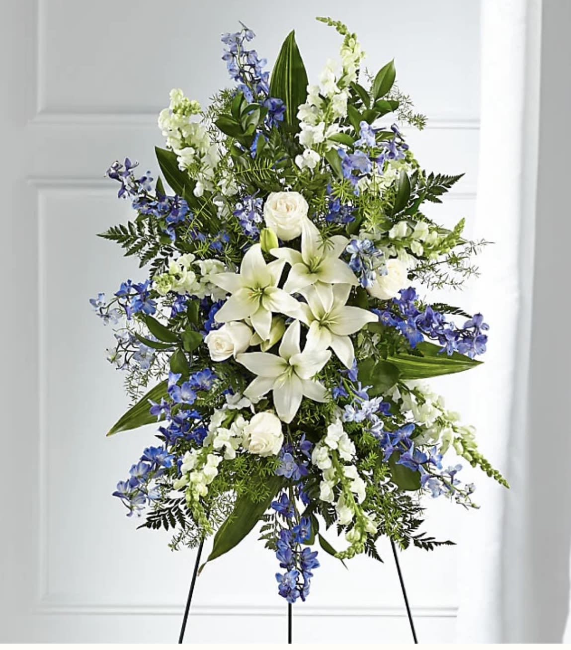 Standing floral spray with white lilies, roses, and blue flowers