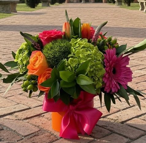 Colorful bouquet with roses, gerbera daisy, hydrangea, and tulips in a wrapped vase