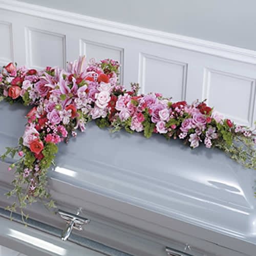 Pink and white floral spray draped over a casket