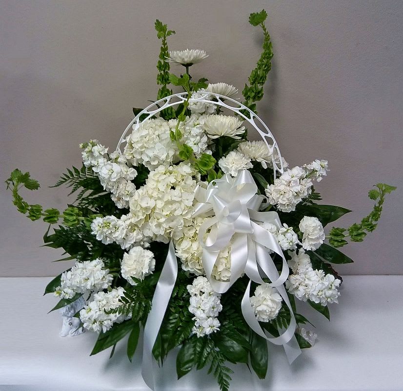 White floral sympathy arrangement with a satin ribbon and arch handle