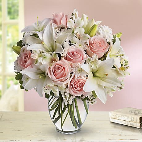 Pink roses and white lilies arranged in a clear glass vase
