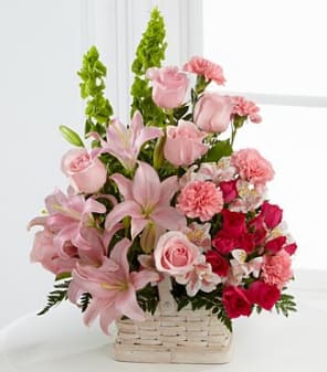 Pink lilies, roses, and carnations in a white basket