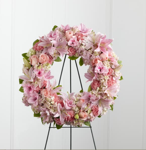 Pink floral wreath on a black stand