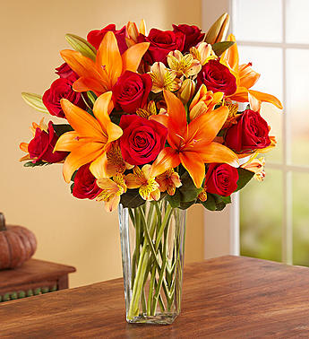 Bouquet of red roses and orange lilies in a clear glass vase
