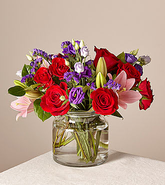 Bouquet of red roses and pink lilies in a clear glass vase