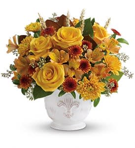 Low round arrangement of yellow roses and orange mums in a white ceramic bowl