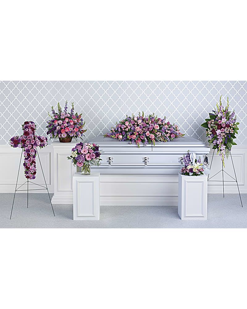 Funeral casket surrounded by pink and purple floral sprays