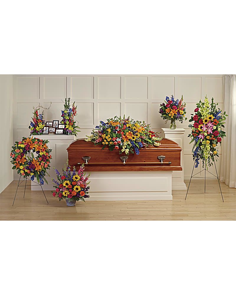 Colorful funeral casket spray with standing floral tributes