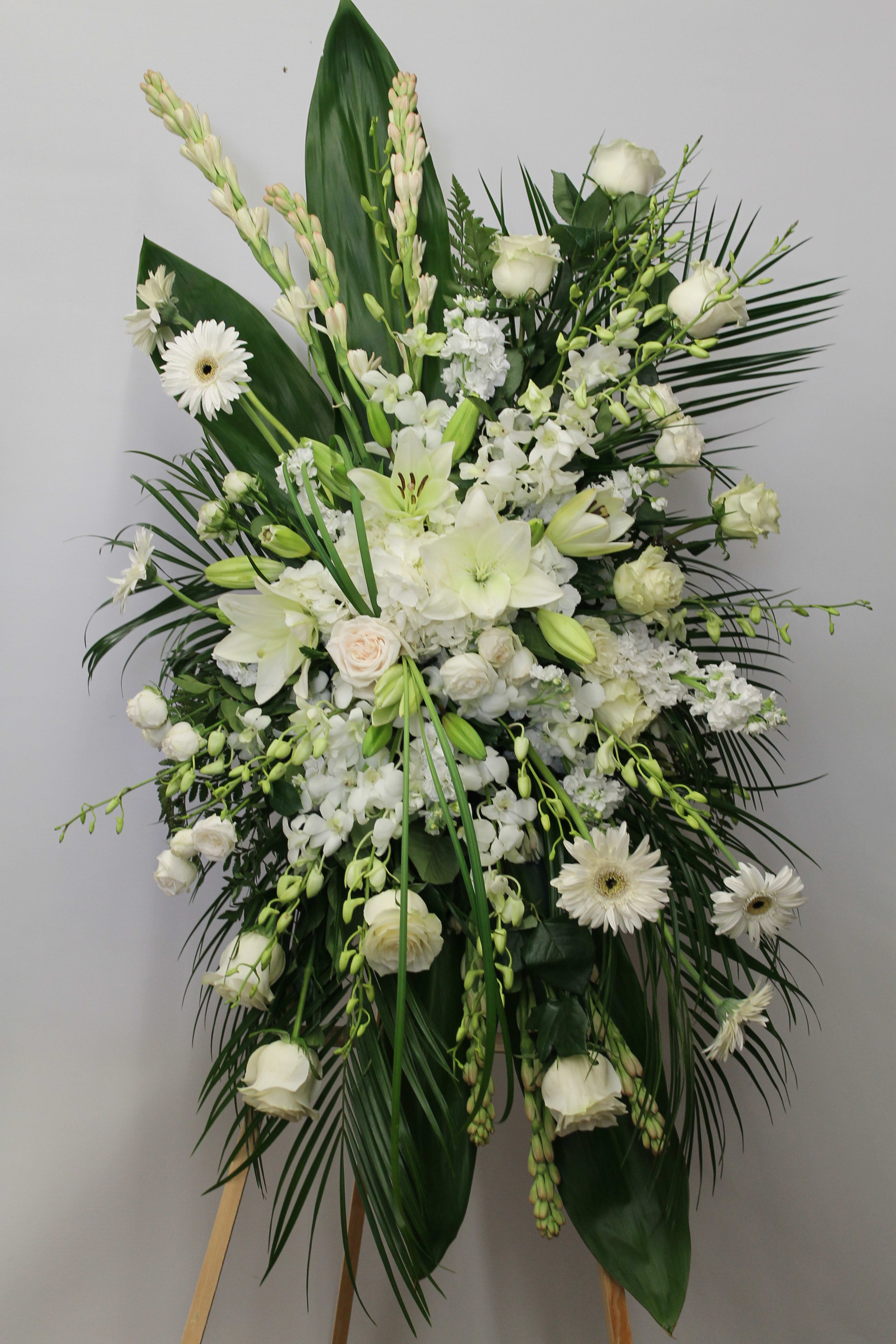 Large white funeral spray with lilies, roses, and gerbera daisies
