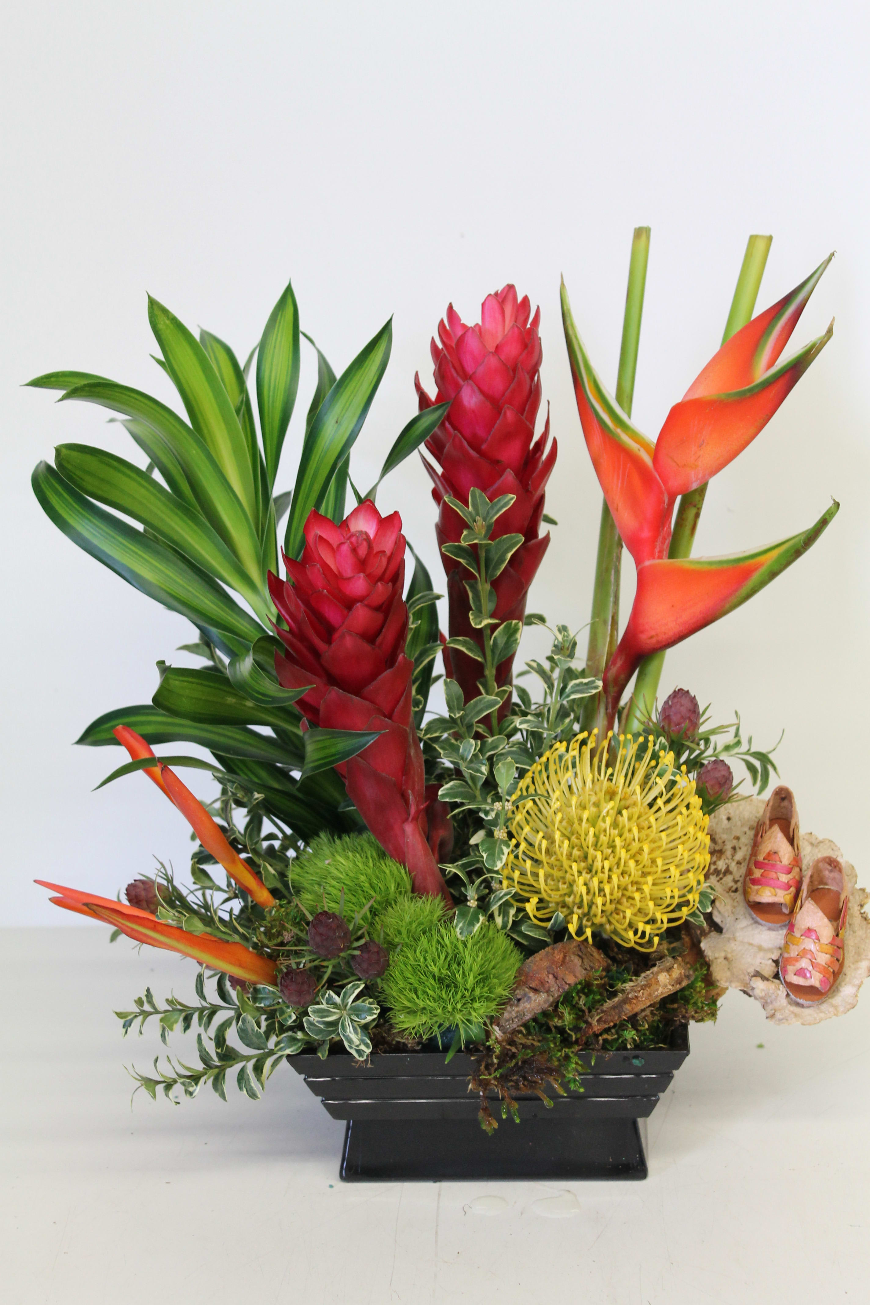 Tropical flower arrangement with red ginger and orange heliconia in a black vase