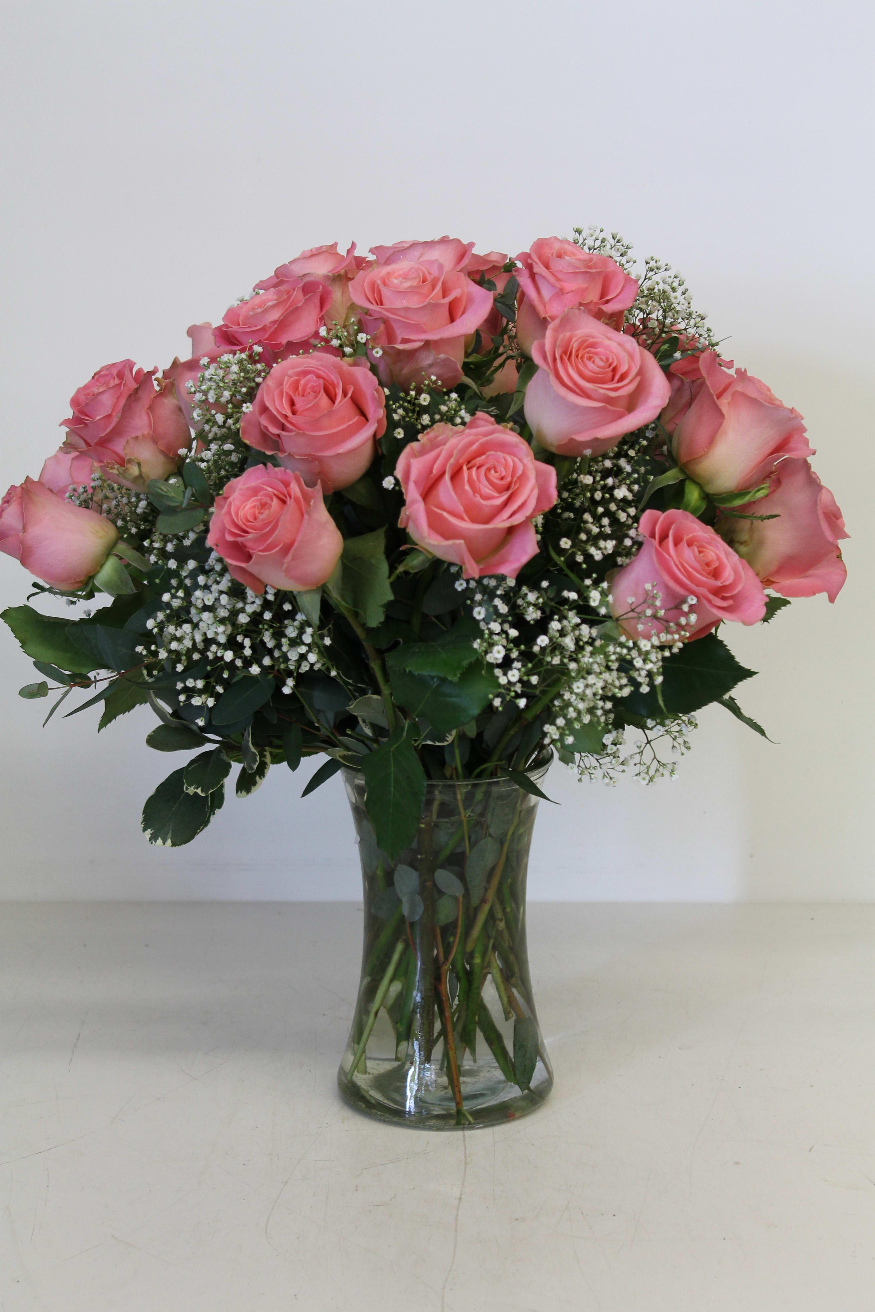 Pink roses arranged in a clear glass vase with baby's breath