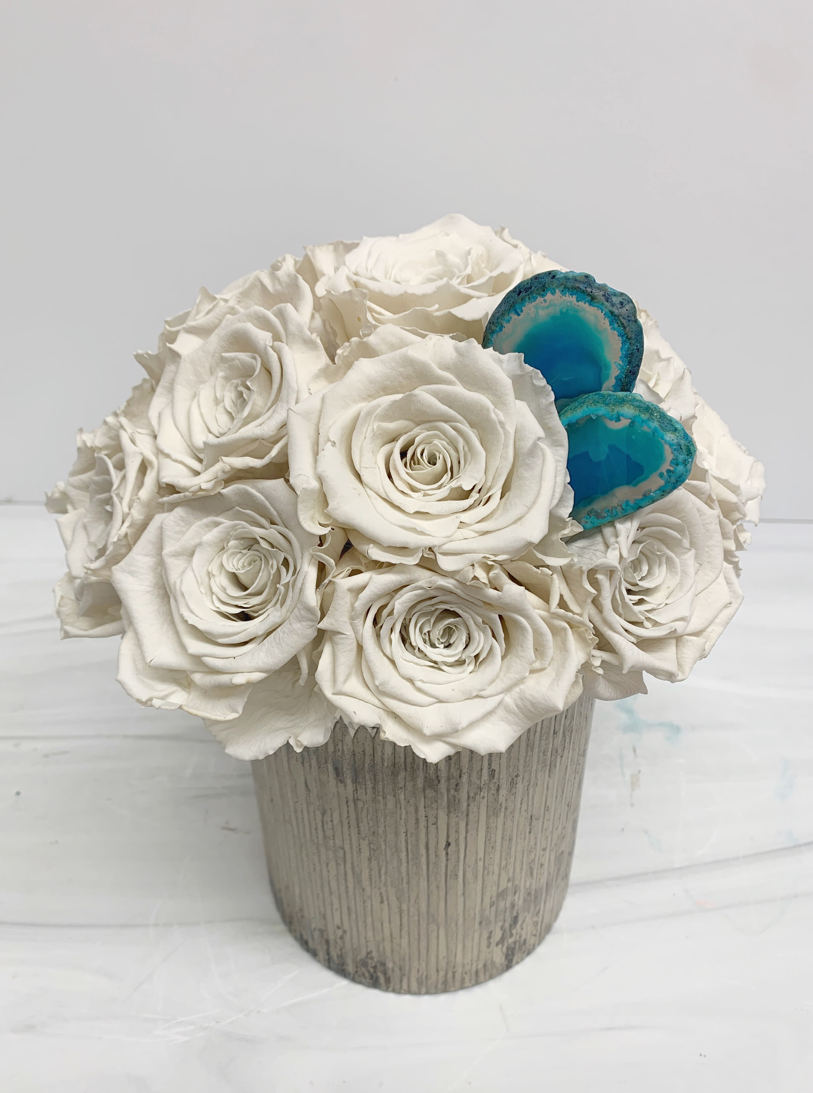 White rose arrangement in a ribbed vase with two blue agate accents