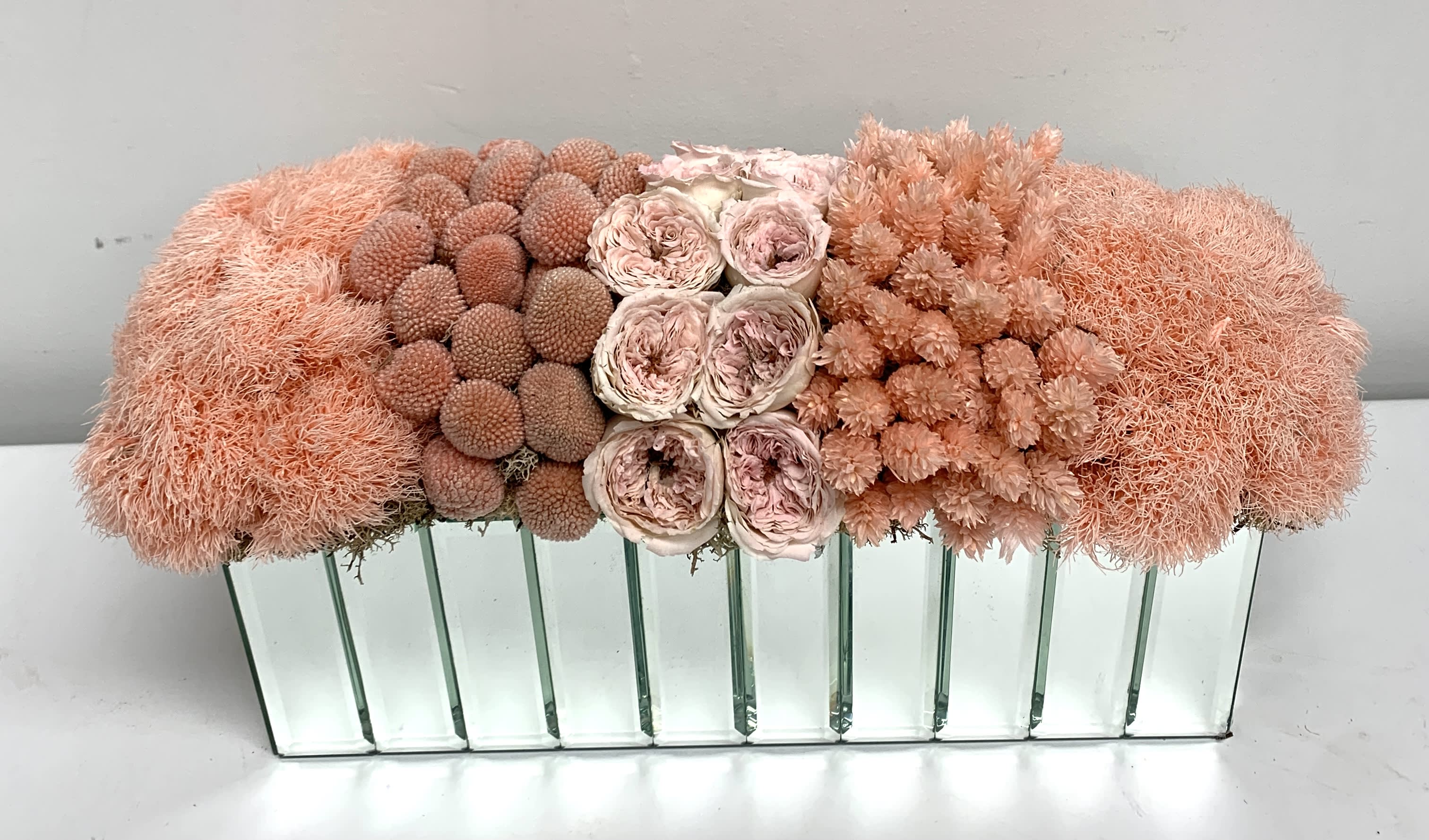 Peach and blush floral arrangement in a mirrored rectangular vase