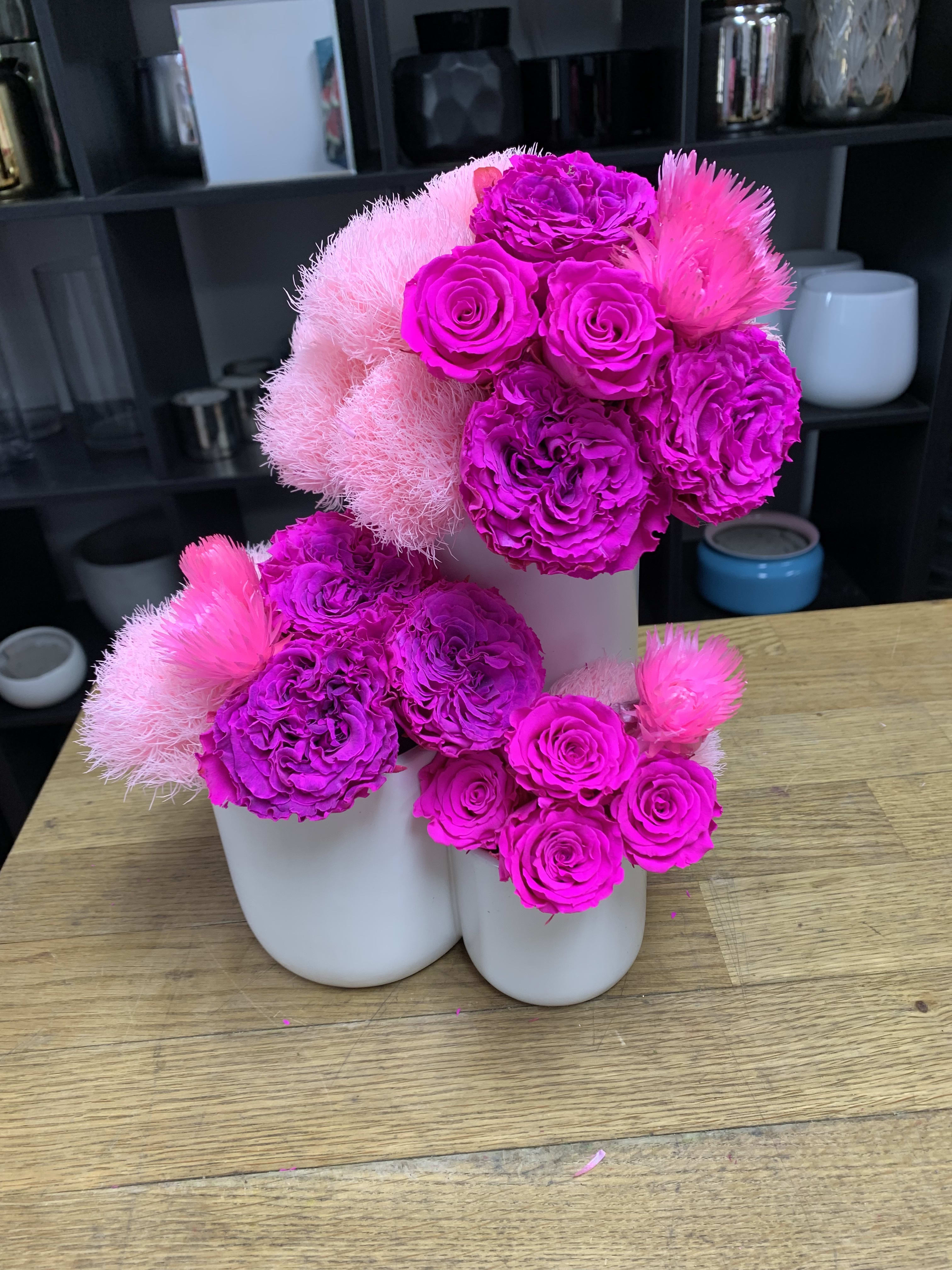 Bright pink floral arrangement in white vases with roses and fluffy blooms