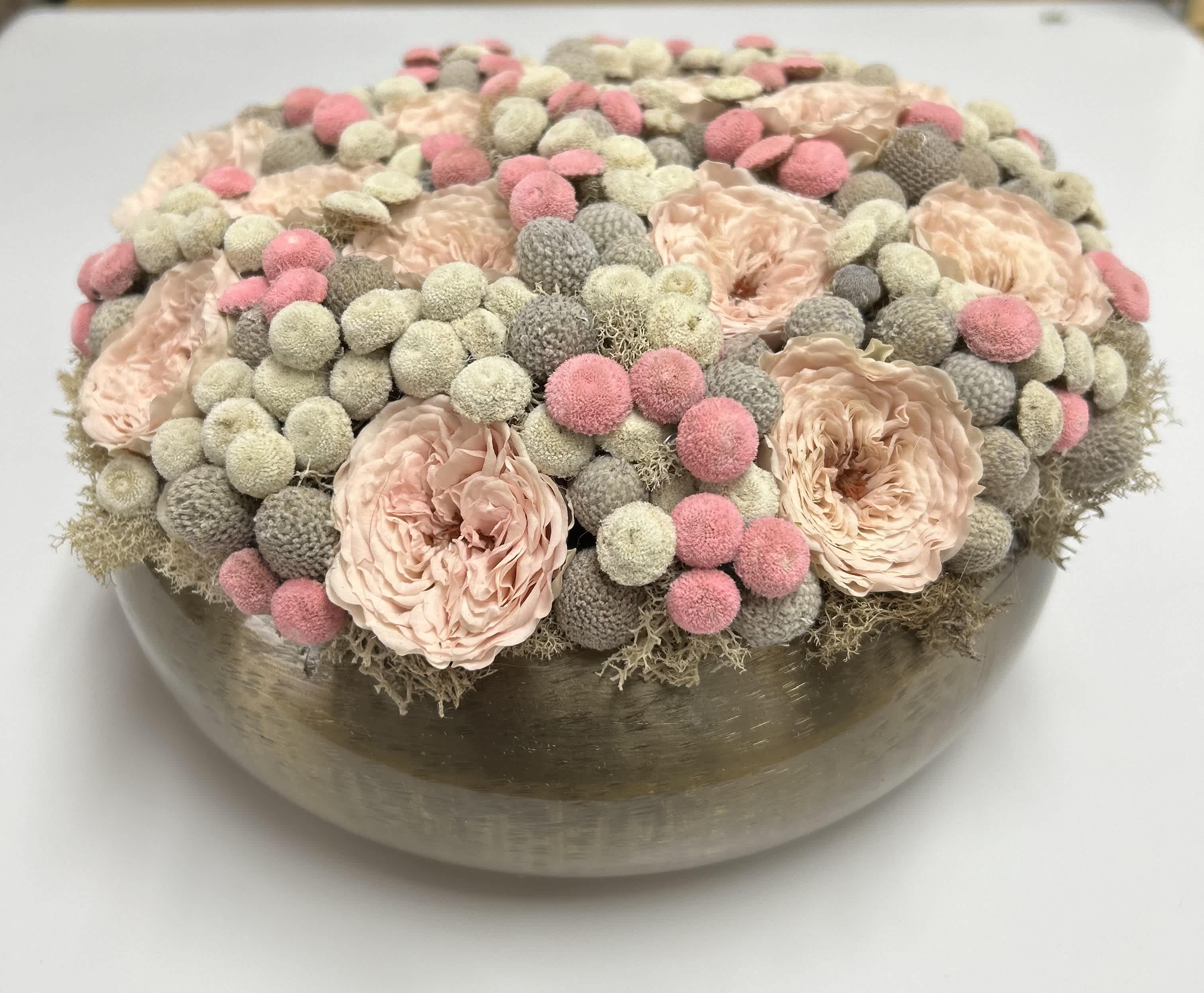 Round floral arrangement in a low metallic bowl with blush and pink blooms