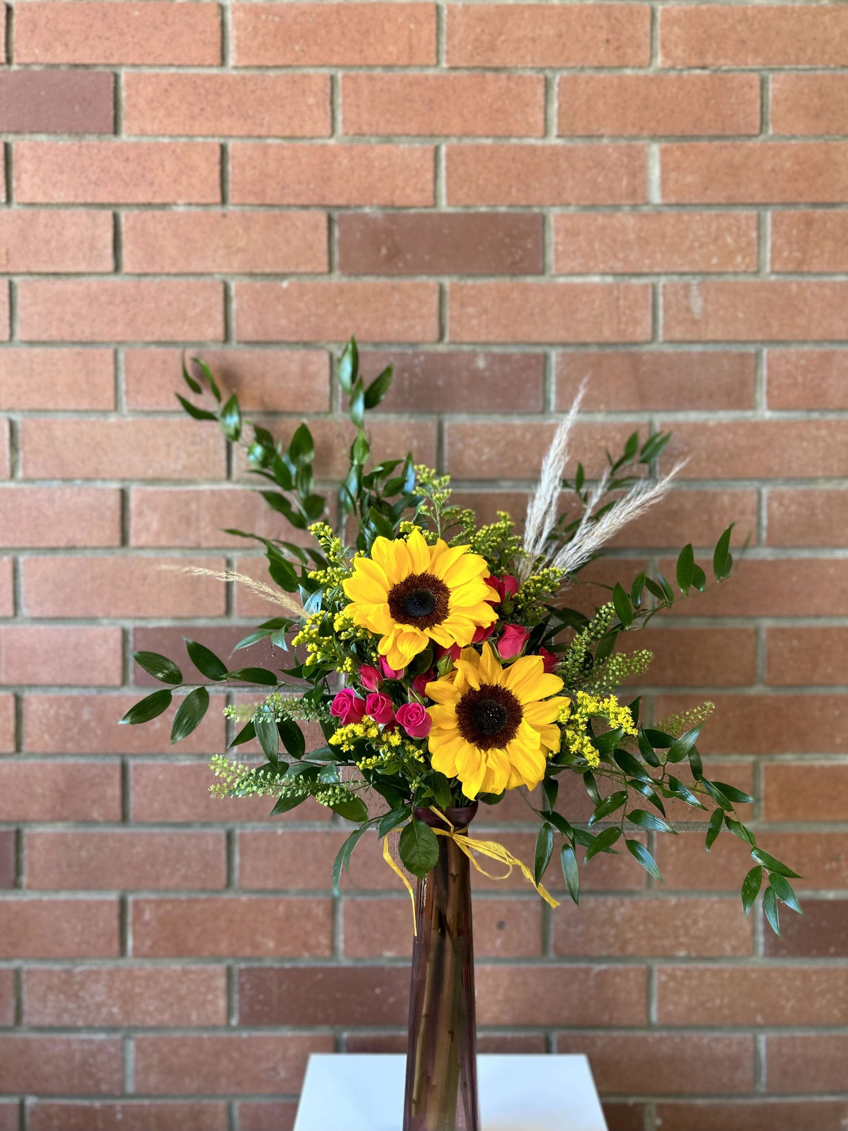 Sunflower and pink rose arrangement in a tall vase
