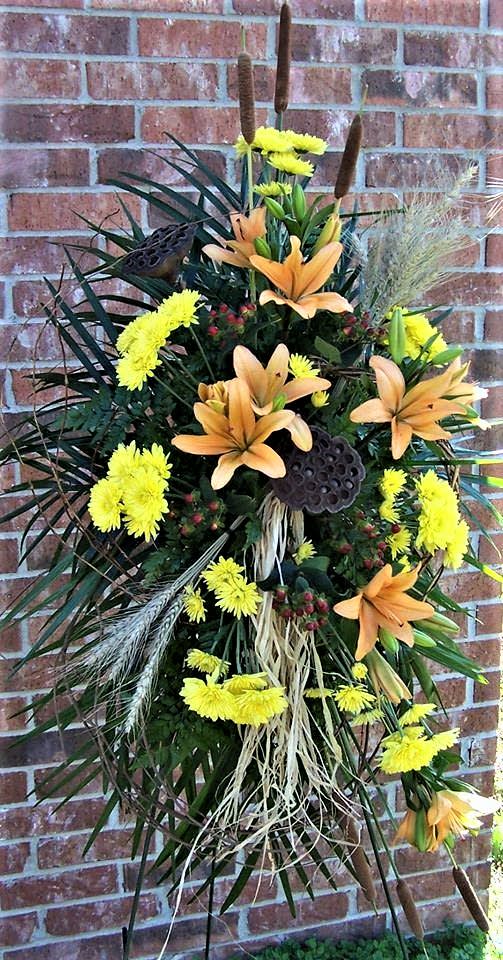 Autumn Bliss - A beautiful standing spray design with orange lilies, poms, pods, wheat and other beautiful blooms to send to someone that loved the outdoors. 