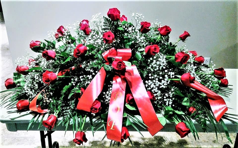 Large casket spray of red roses with pink ribbons