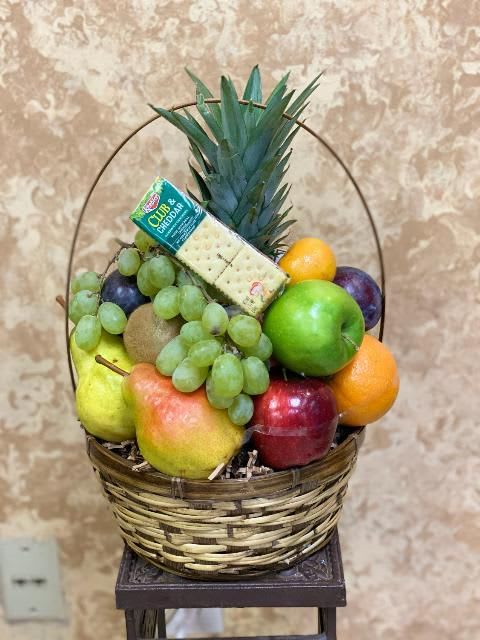 Fruit basket with grapes, apples, oranges, pears, kiwi, pineapple, and crackers
