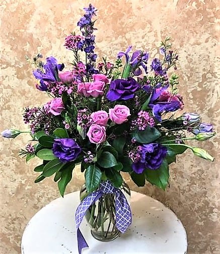 Pink and purple bouquet in a glass vase with a ribbon