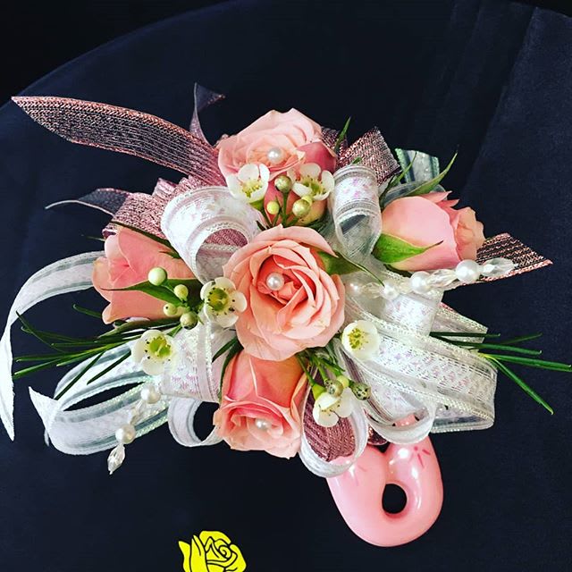 Pink rose corsage with white ribbon and pearl accents