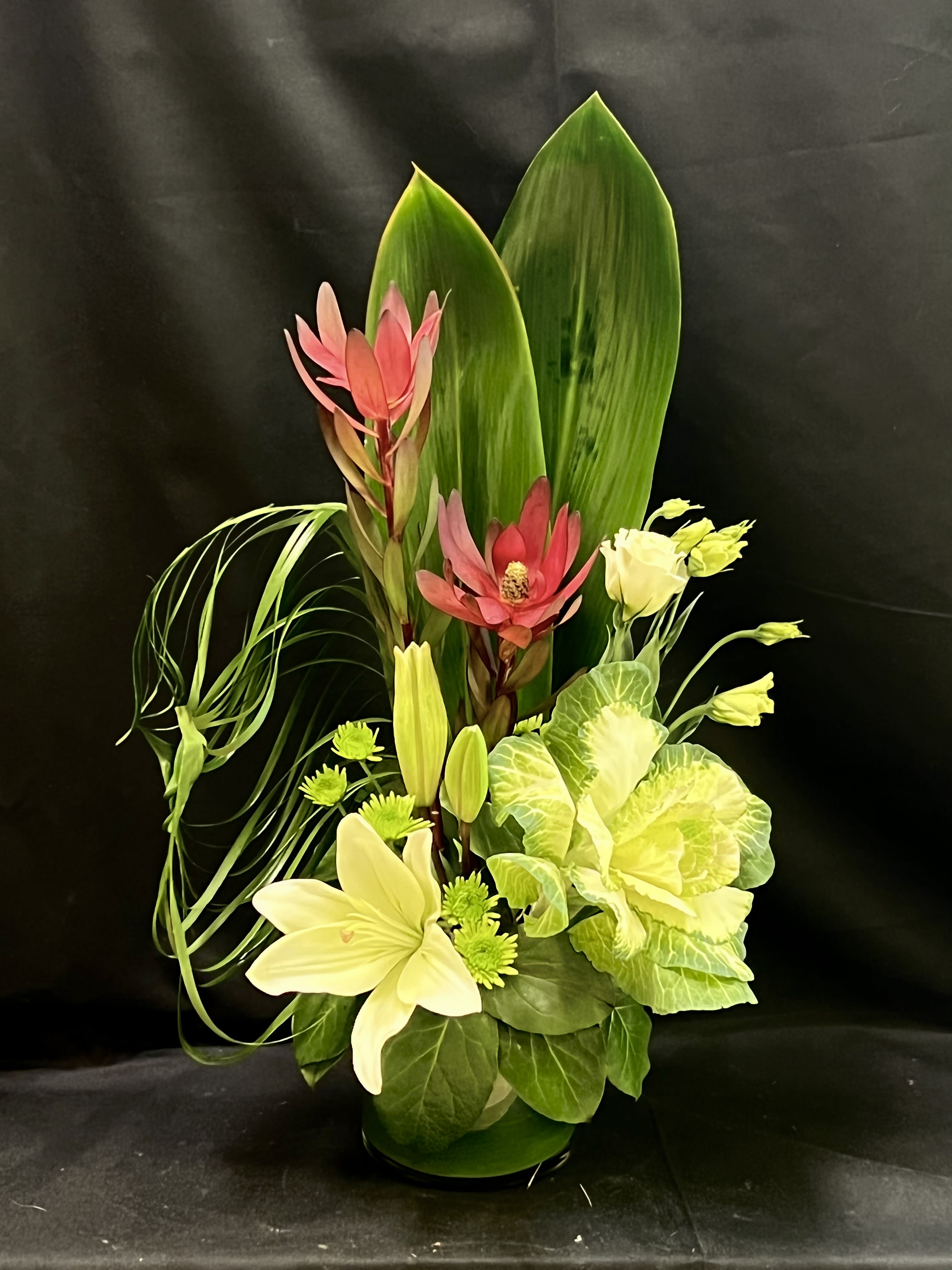 Tropical floral arrangement with pink and cream blooms in a vase