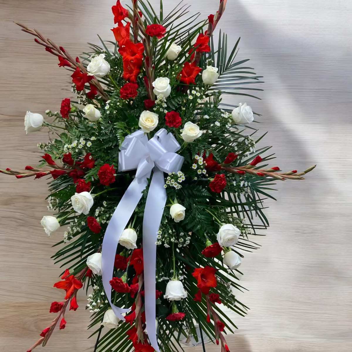 Strength of Endurance - Our strength of Endurance standing spray is a great tribute to your loved one that showed remarkable strength throughout their life. Designed with Gladiolus, roses and carnations Lucious greens displayed on an easel.