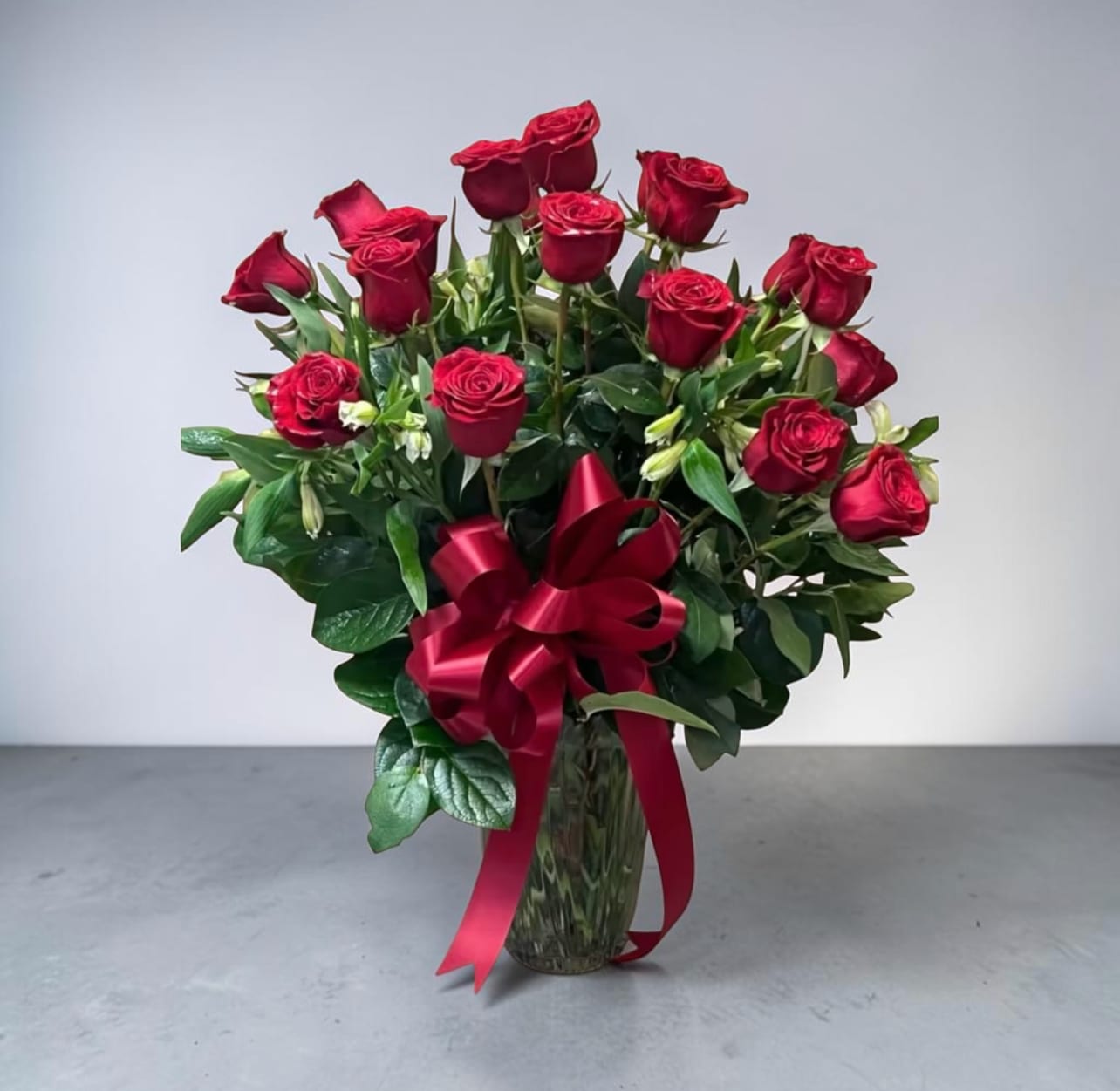 2- Dozen Red Rose Bouquet - Beautiful 2 dozen red rose bouquet for any occasion. Designed in a beautiful clear glass vase with 3 different types of greens and beautiful filler.