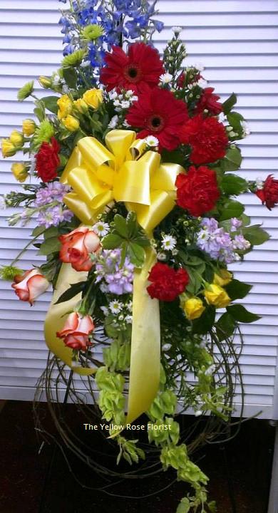 Tall standing floral spray with red, yellow, blue, and lavender blooms