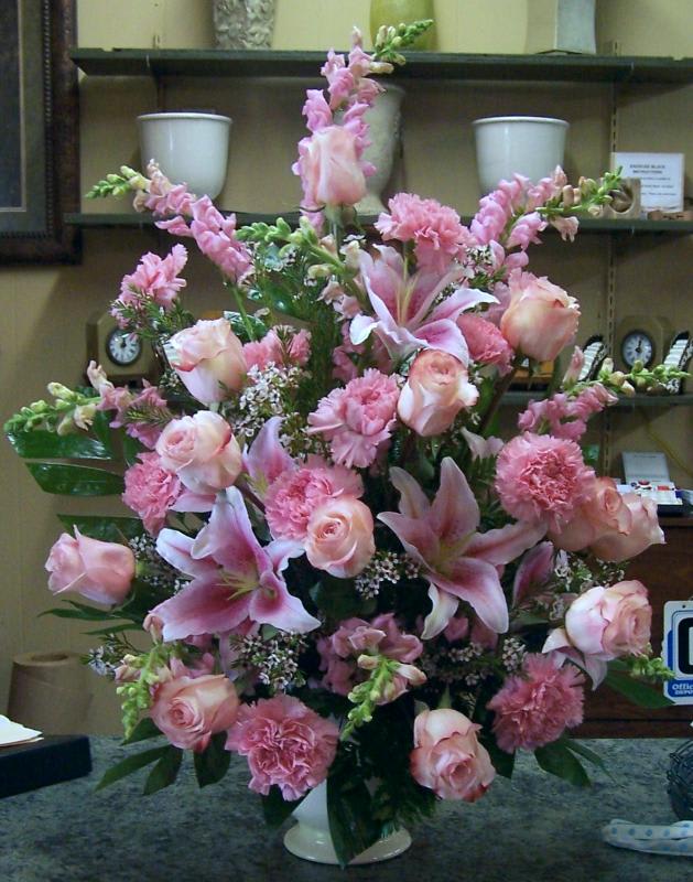 Pink floral arrangement with roses, lilies, and carnations in a white vase
