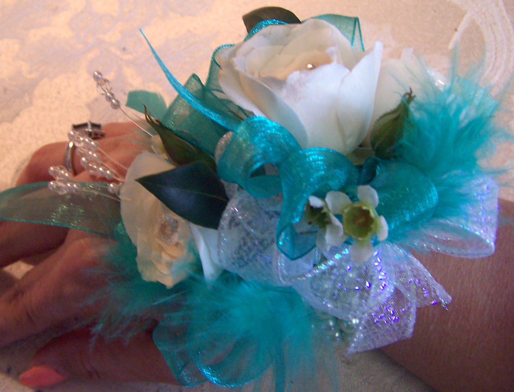 White rose corsage with turquoise ribbon and feathers
