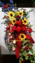 Standing floral spray with sunflowers and red roses on a white easel
