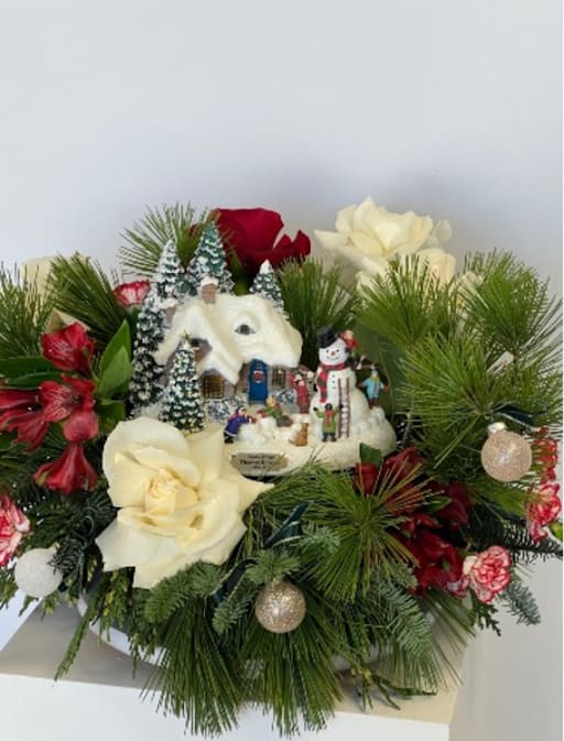 Christmas floral arrangement with white and red roses and a snowy village ornament