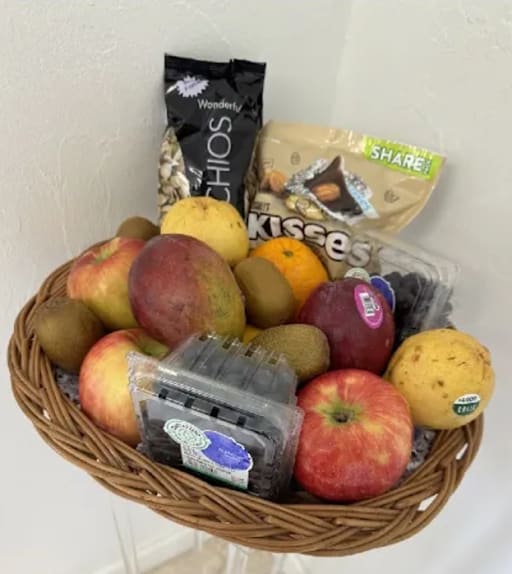 Fruit basket with apples, kiwis, oranges, and packaged snacks