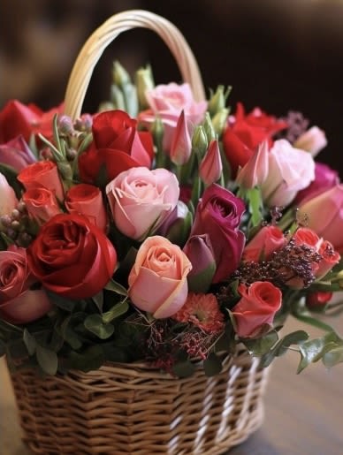 Basket of mixed roses and tulips in pink and red tones