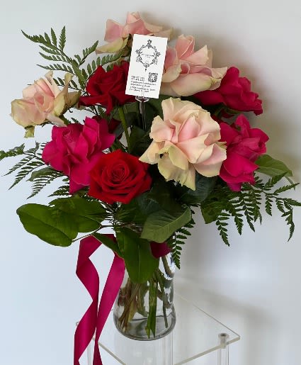 Bouquet of red and blush roses in a glass vase with a pink ribbon