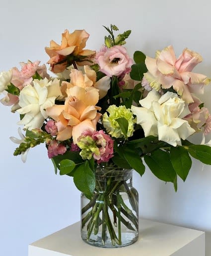 Mixed pastel flowers arranged in a clear glass vase