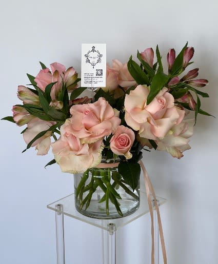 Pink roses and alstroemeria in a glass vase with a ribbon