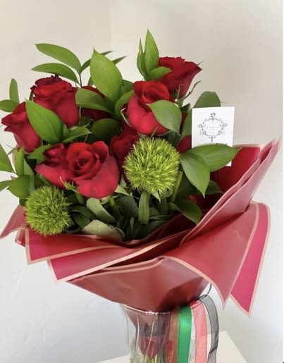 Bouquet of red roses with green accents wrapped in pink paper