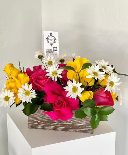 Pink and yellow roses with white daisies in a wooden box