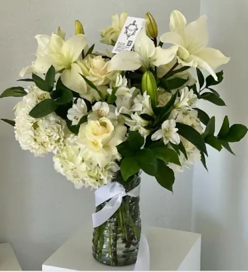 White floral bouquet in a glass vase with a ribbon